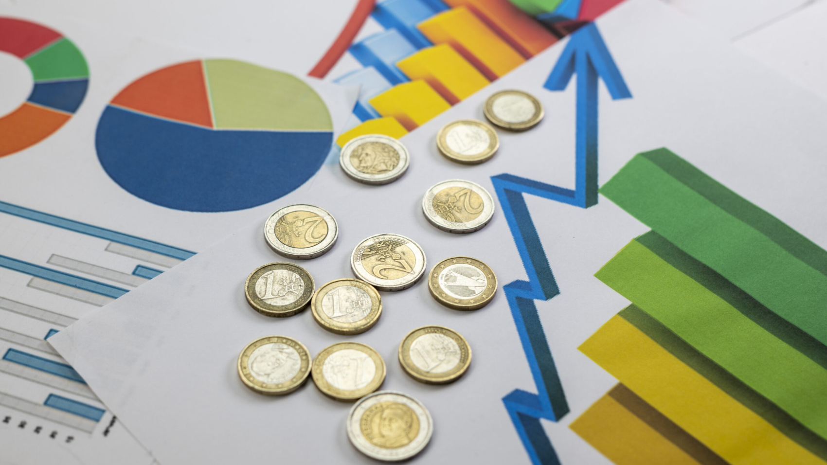 A high-angle shot of a euro coins, and statistics in the graph on a white table