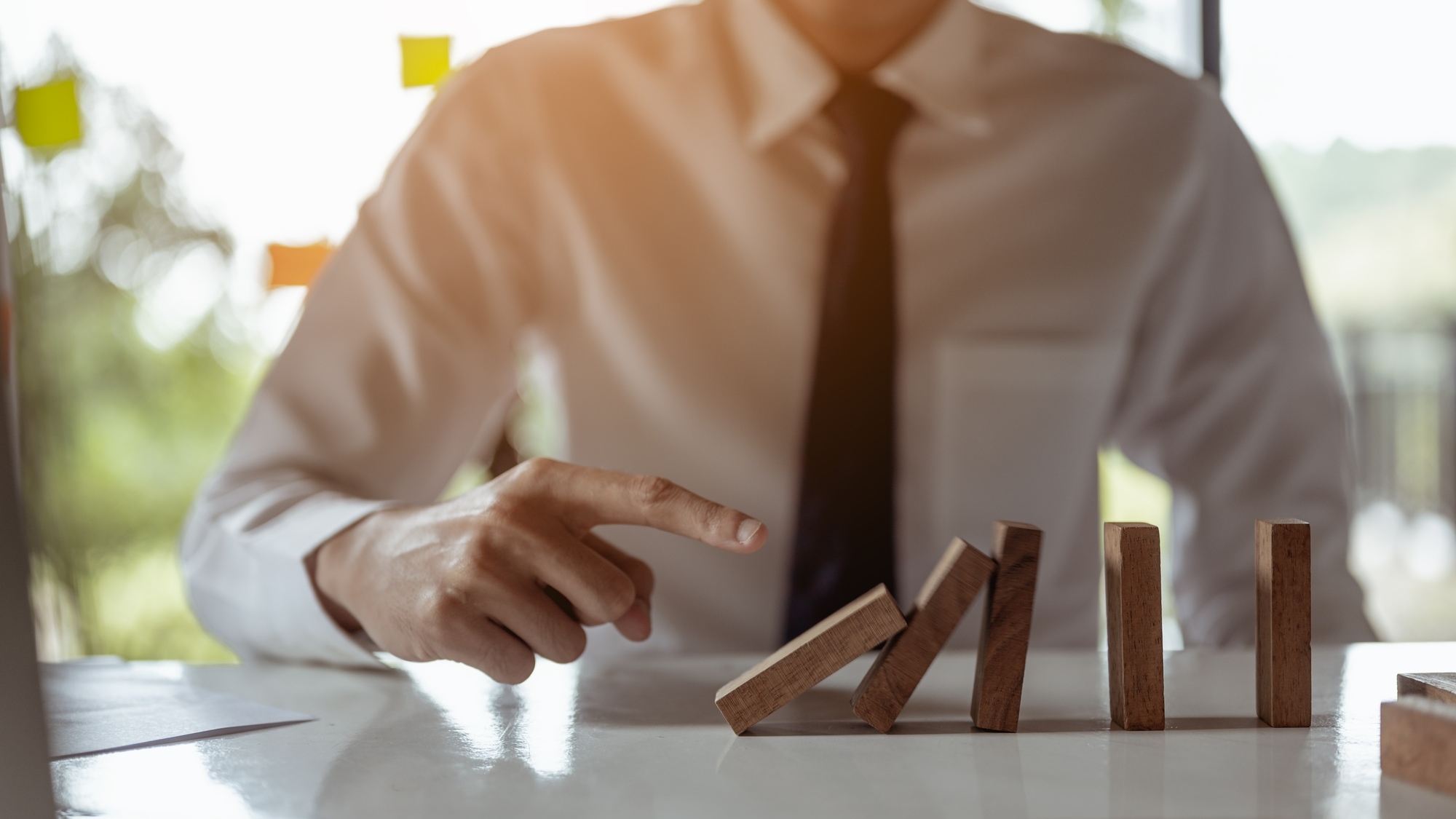 Businessman pulling or placing long wooden blocks in a modern office Indicates the impact