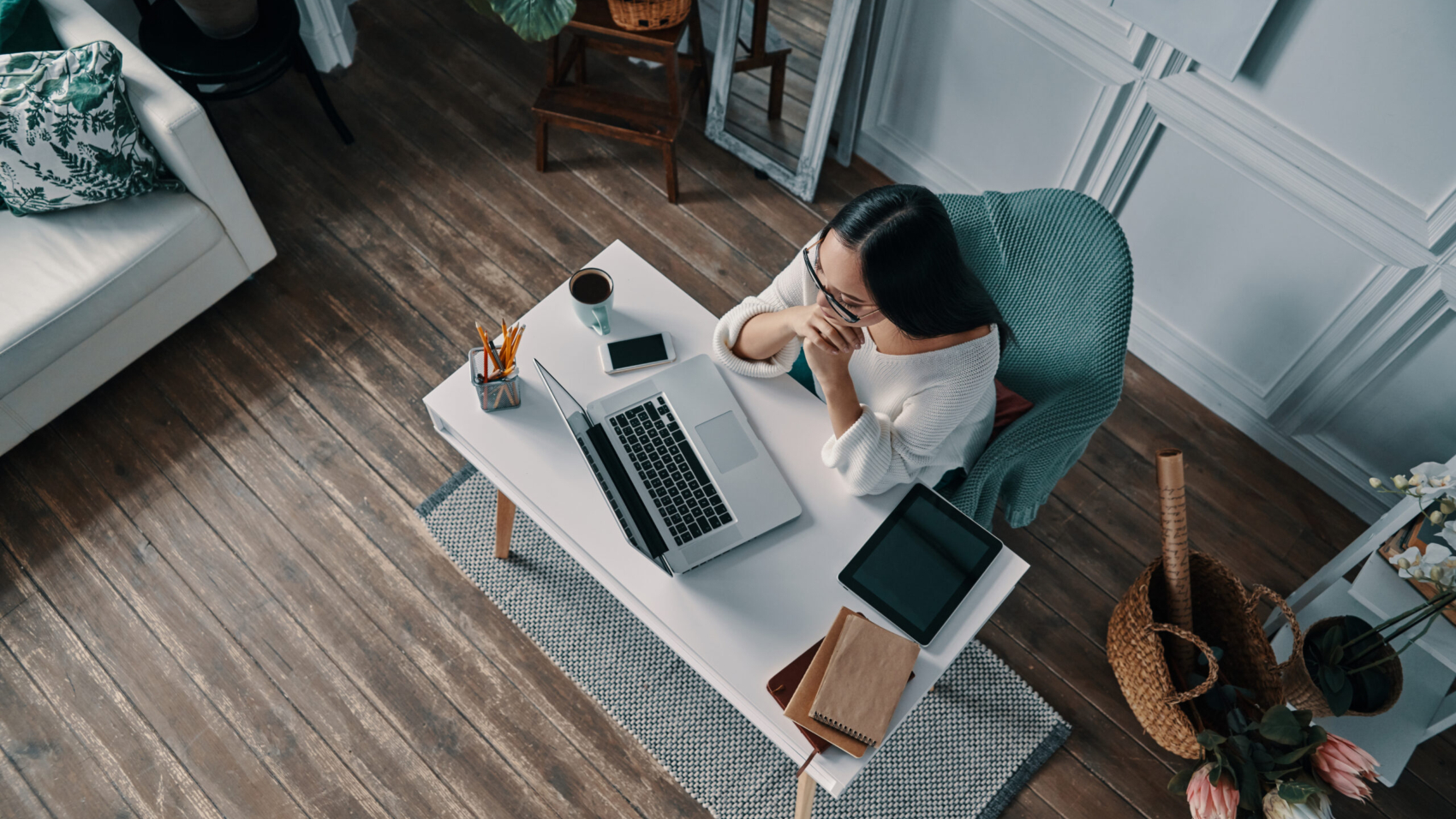 Hard decision to make. Top view of beautiful young woman working using computer while sitting in home office